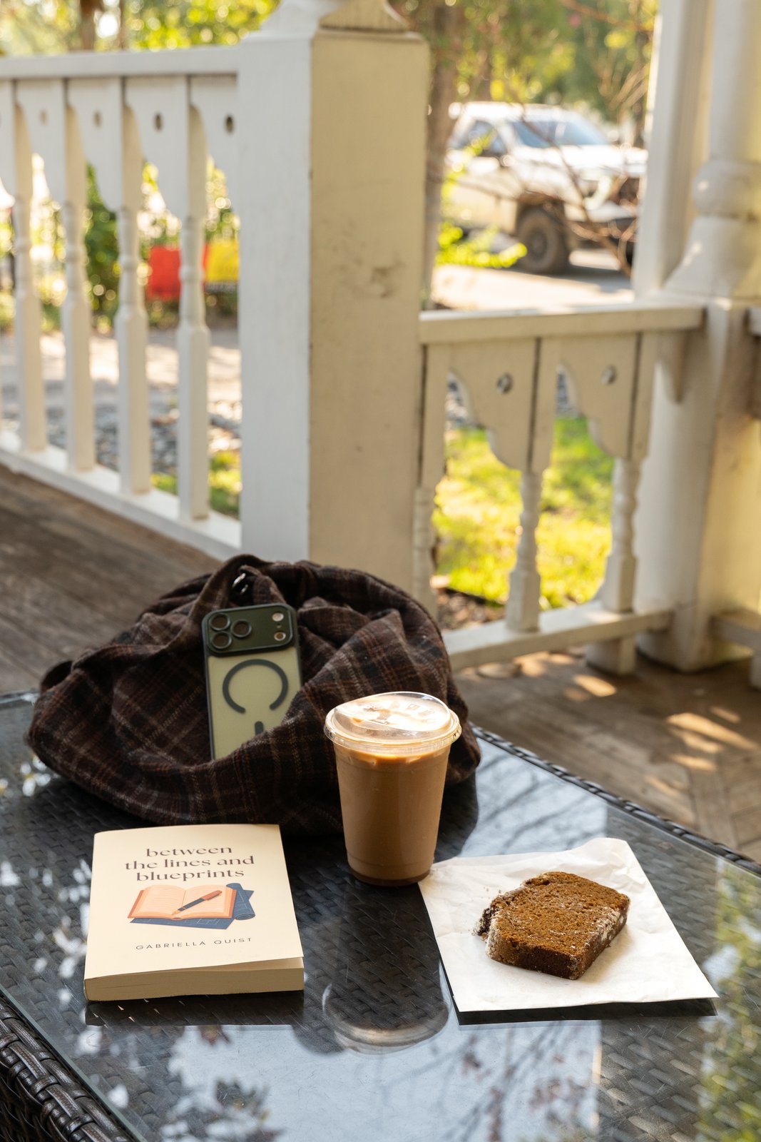 Between the Lines and Blueprints on a porch table with a latte and a cookie